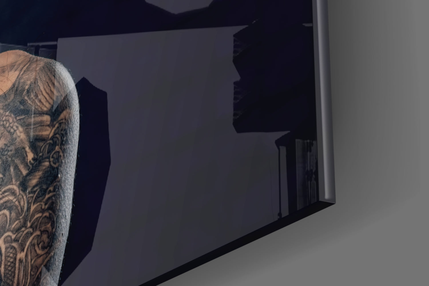 Person with tattooed arm viewing dark frosted glass wall art panel mounted indoors.