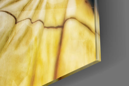 Close-up of translucent amber and yellow glass with brown veining detail against gray background.
