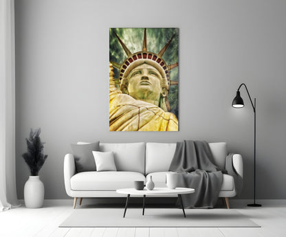 Statue of Liberty glass wall art displayed above a white sofa in a modern living room, showing upward-angled close-up of the statue's face and torch-bearing arm.