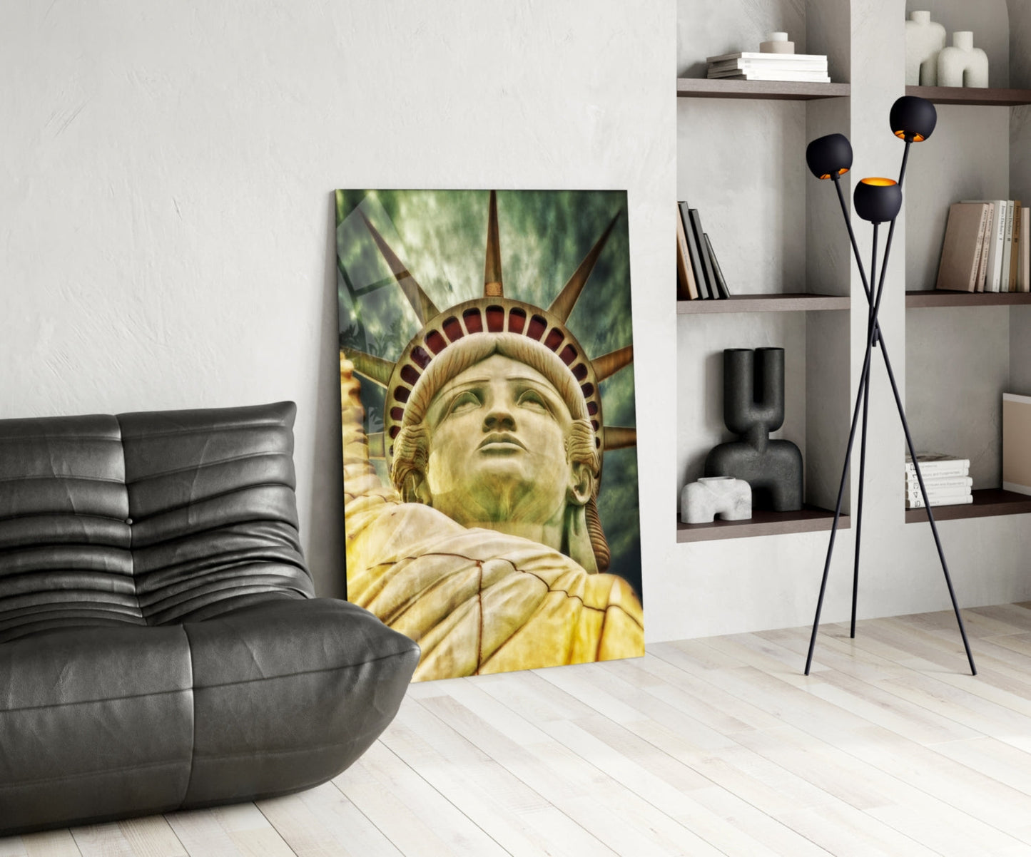 Glass wall art depicting the Statue of Liberty's face and torch displayed in a modern living room with black leather furniture and shelving.