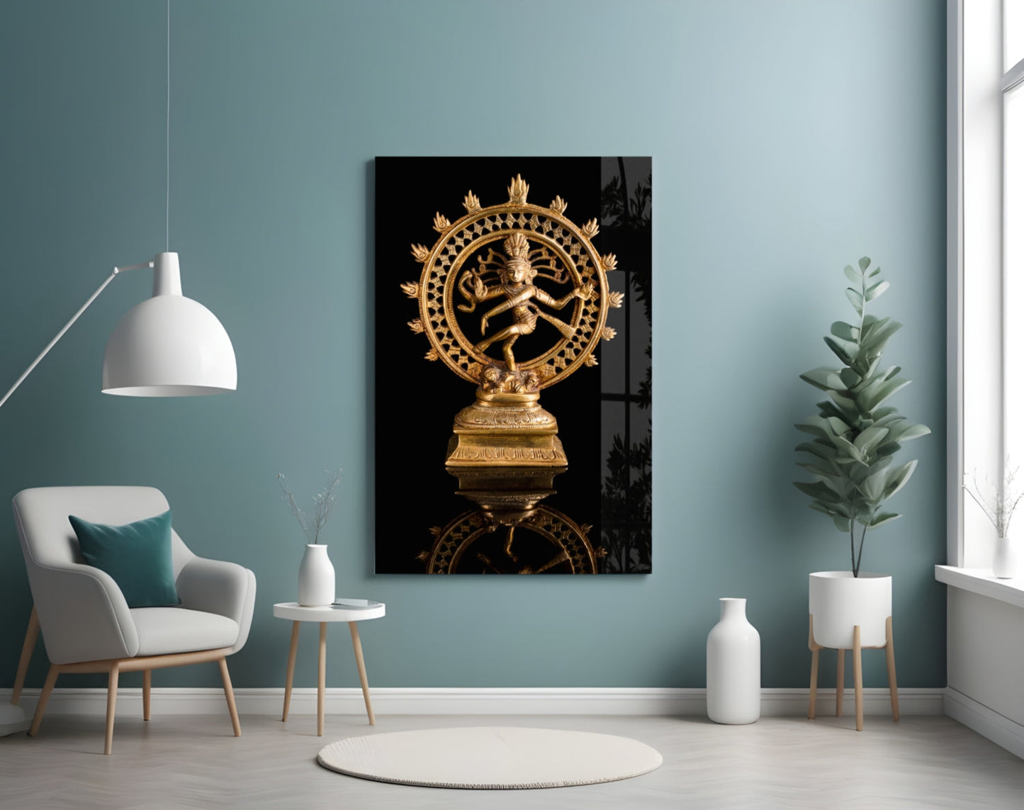 Golden Shiva Nataraja statue displayed on black glass art mounted in a modern teal room with white furniture.
