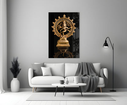 Golden Shiva Nataraja statue displayed on white living room wall above cream sofa with black background.