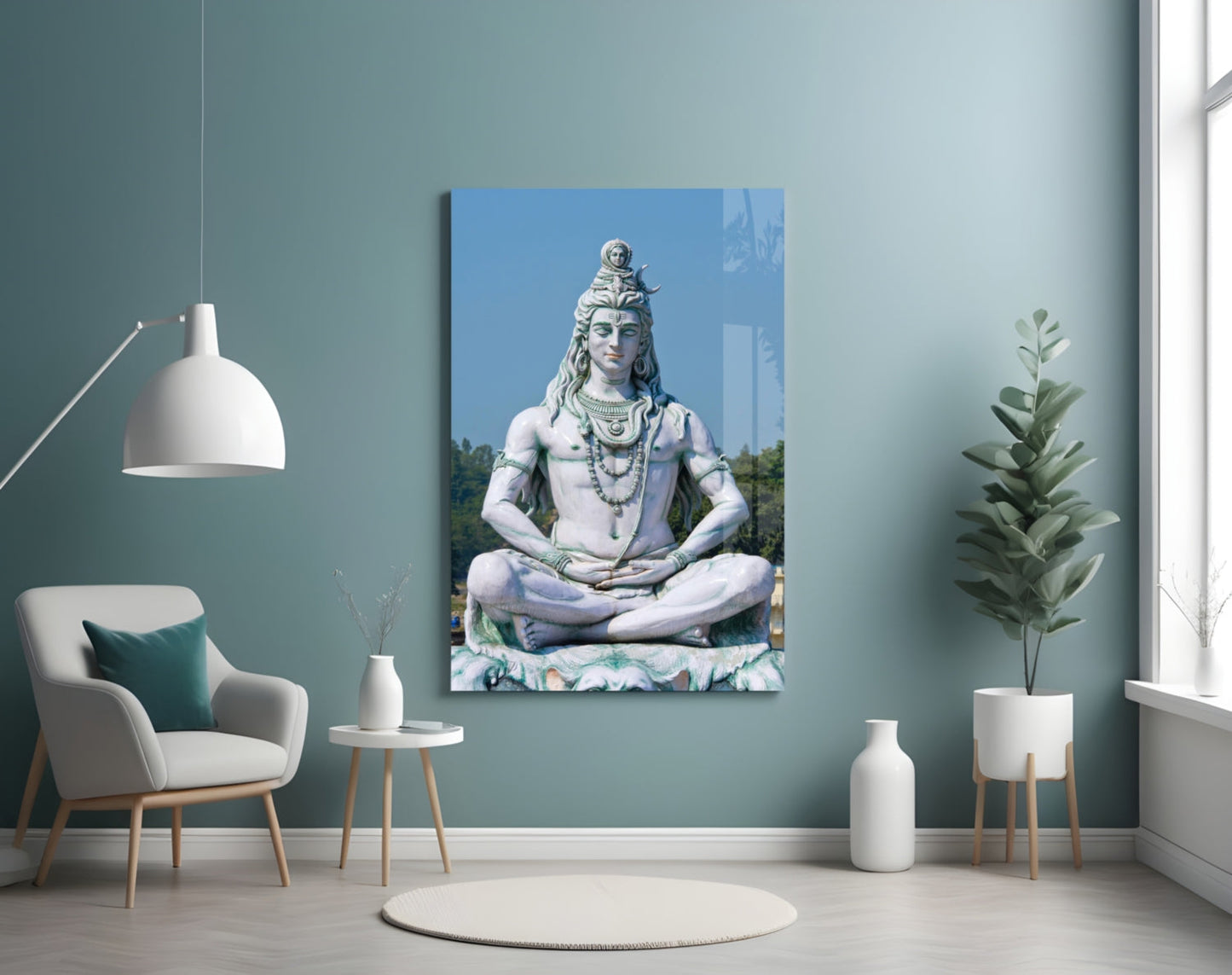 Glass wall art depicting a white marble statue of Shiva in meditation pose against blue sky, displayed in a serene room setting.