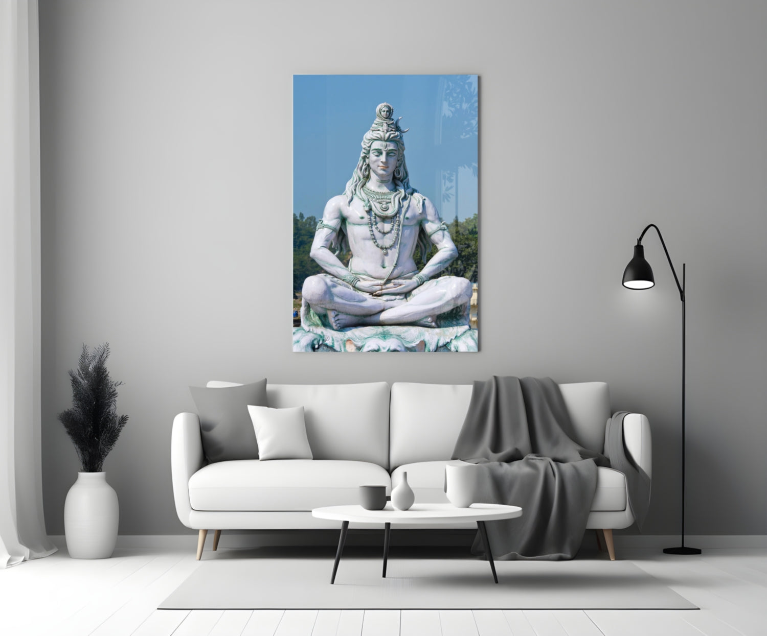 White stone Shiva statue in meditation pose displayed on gallery wall above cream sofa in modern living room interior.