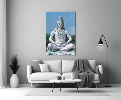White stone Shiva statue in meditation pose displayed on gallery wall above cream sofa in modern living room interior.