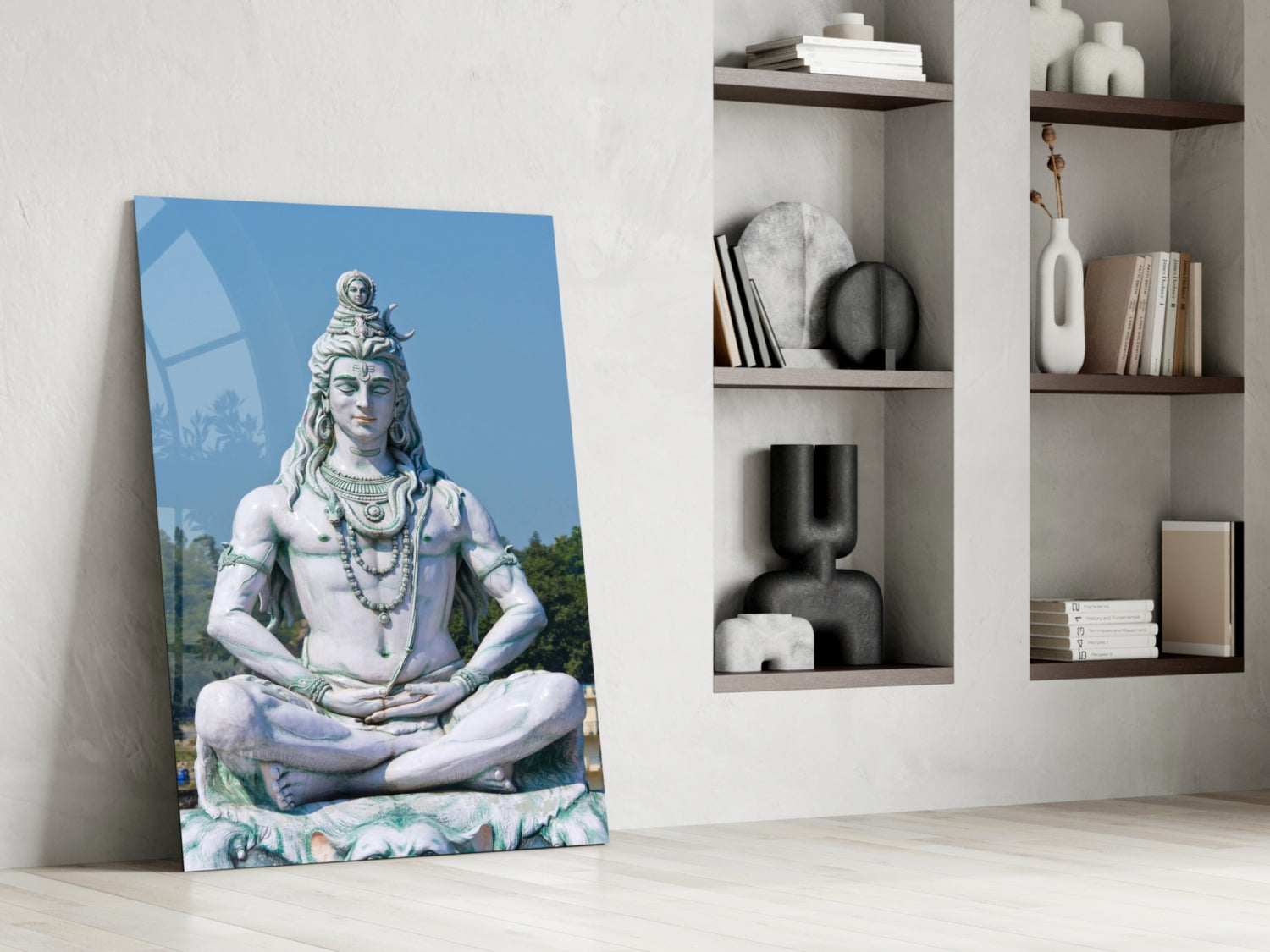 Canvas print of Shiva statue in meditation pose leaning against white wall beside shelving unit with decorative objects.
