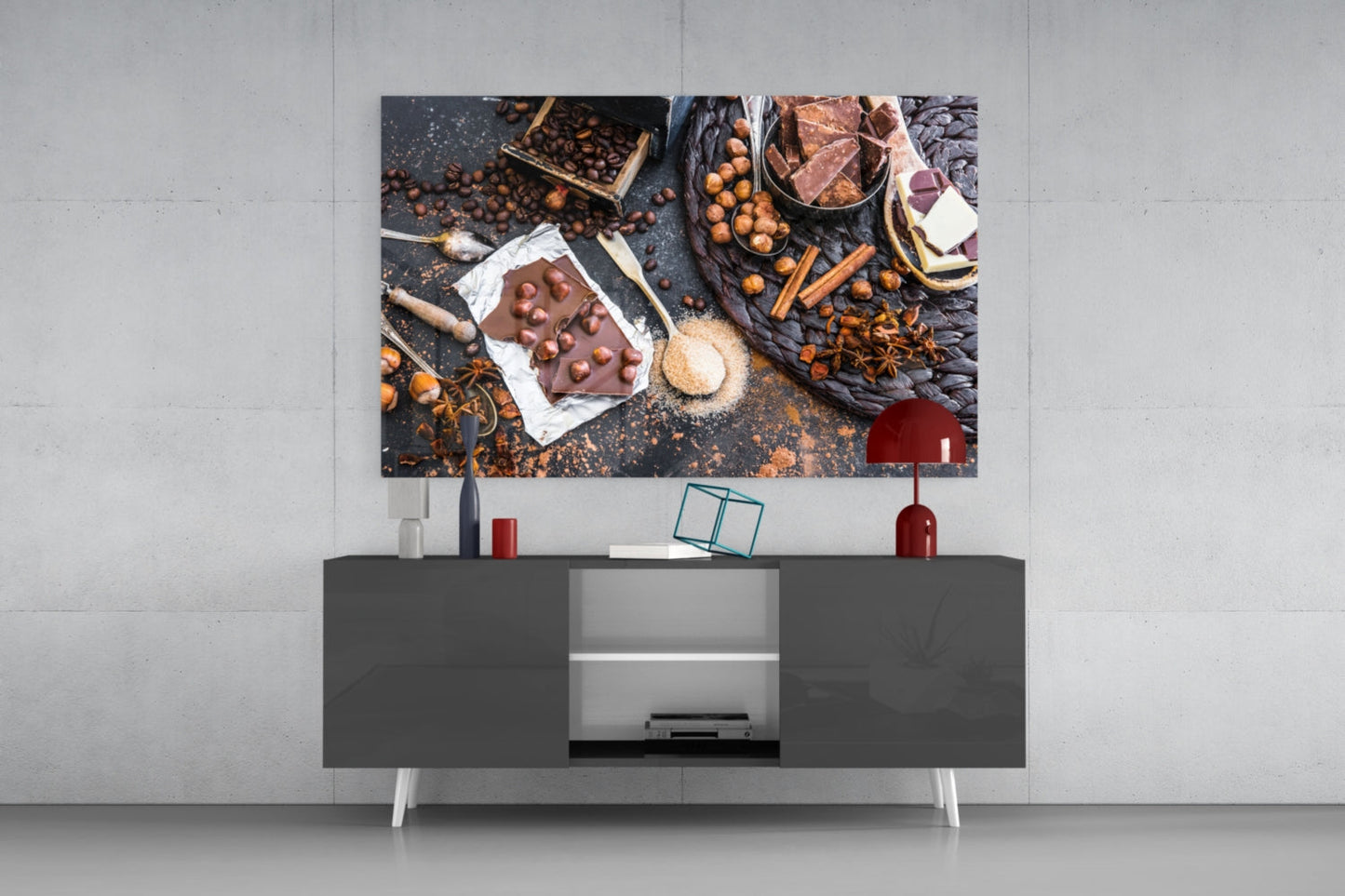Glass wall art displaying chocolate, nuts, and baking ingredients mounted above a dark media console in a modern interior.