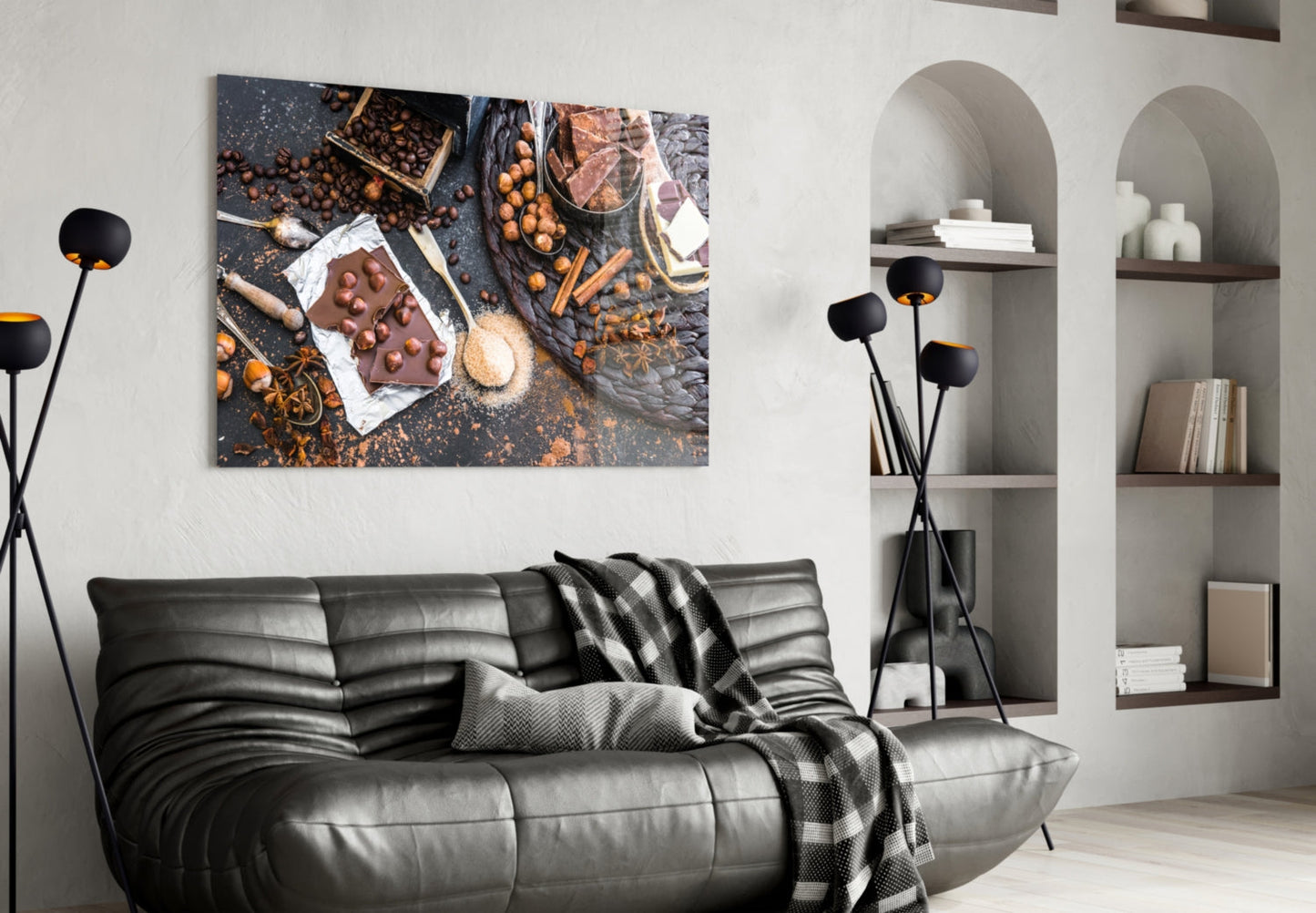 Chocolate glass wall art depicting cocoa beans, chocolate bar, and baking ingredients displayed above black leather sofa in modern living room.