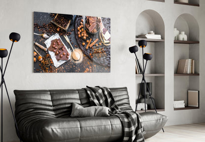 Chocolate glass wall art depicting cocoa beans, chocolate bar, and baking ingredients displayed above black leather sofa in modern living room.