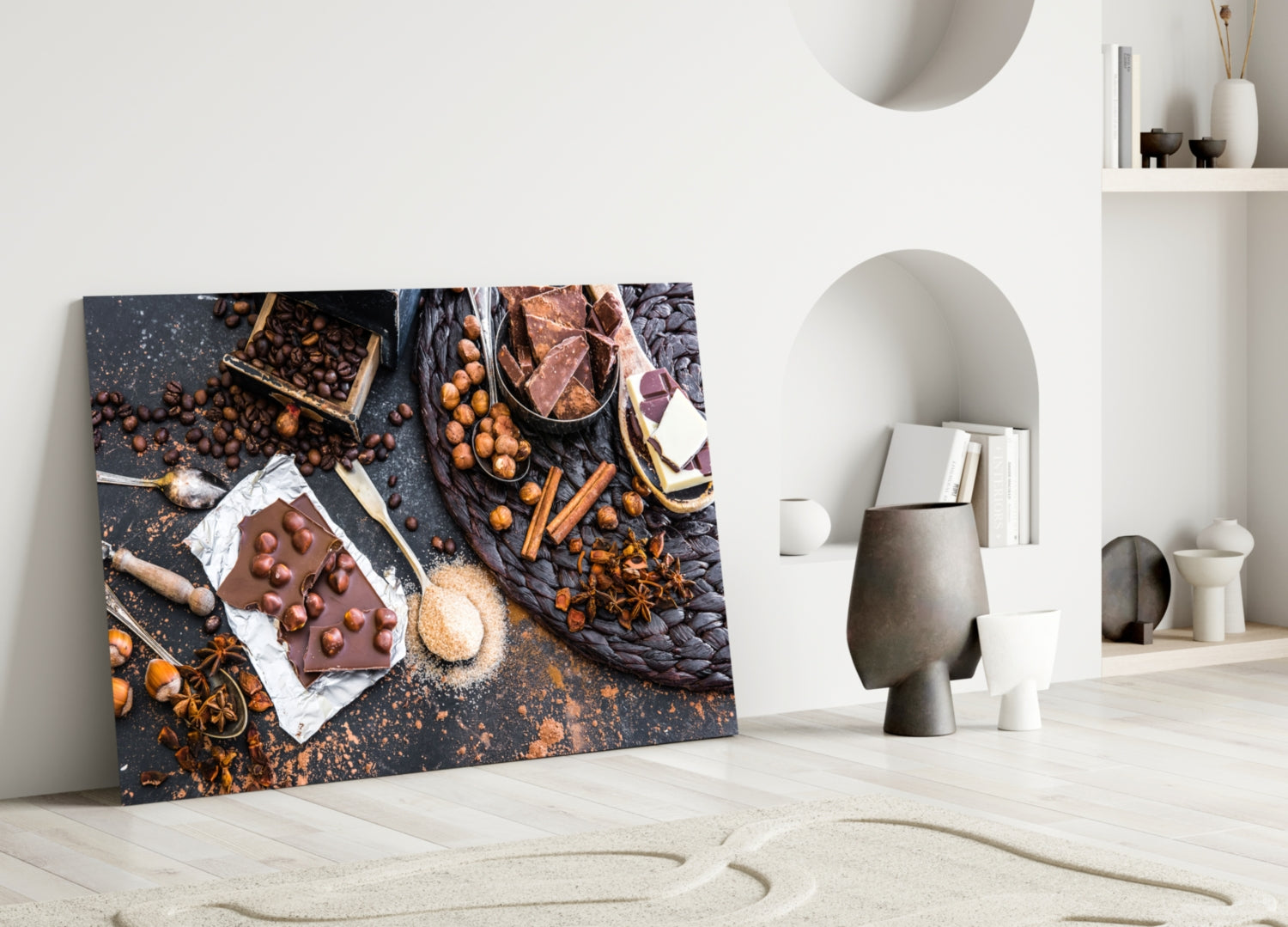 Chocolate glass wall art leaning against white wall displays overhead flat-lay of chocolate bars, nuts, and spices on dark surface.