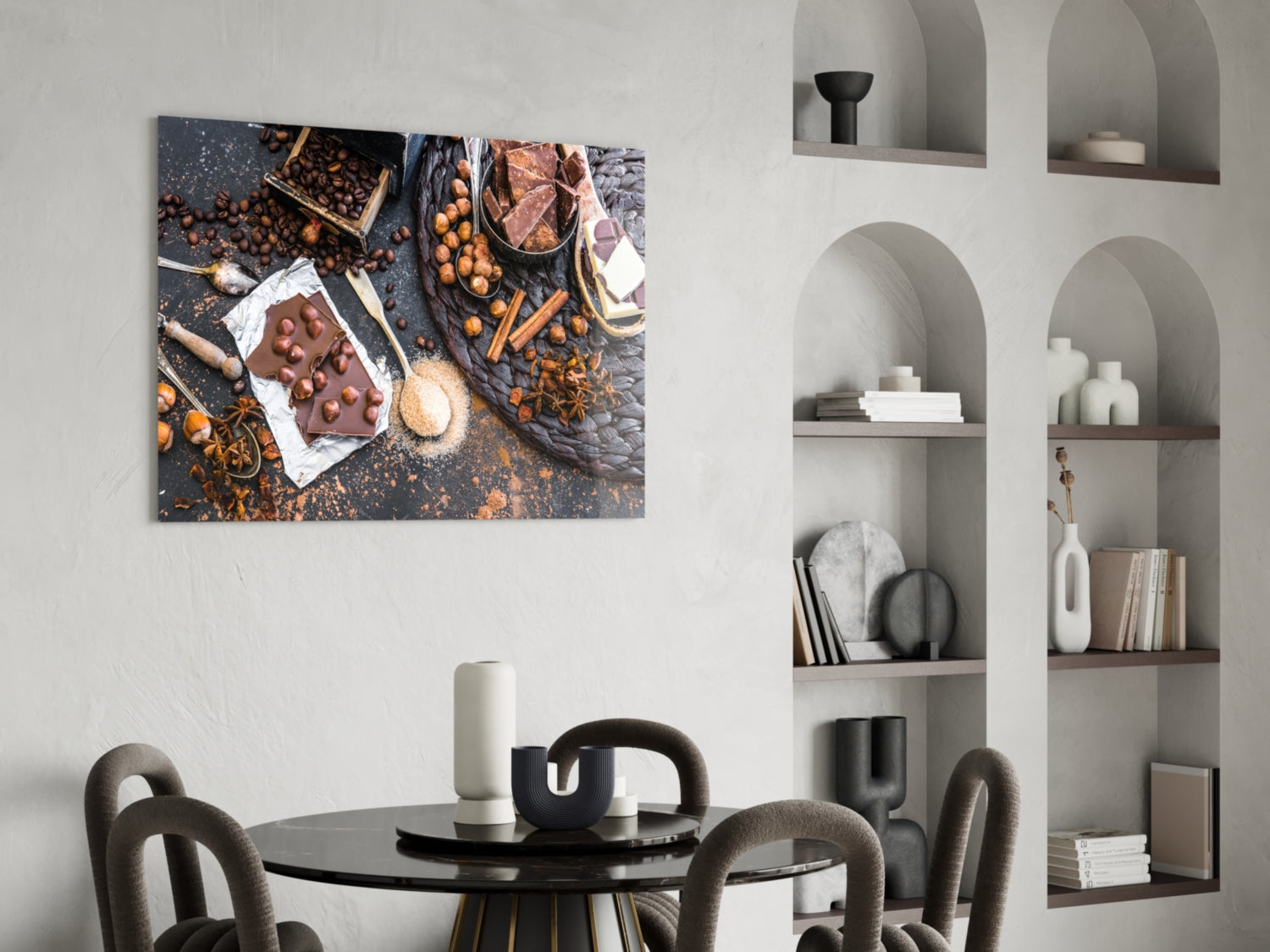Chocolate glass wall art displaying overhead flat-lay arrangement of cocoa beans, chocolate pieces, spices, and baking ingredients hung above a dining table.