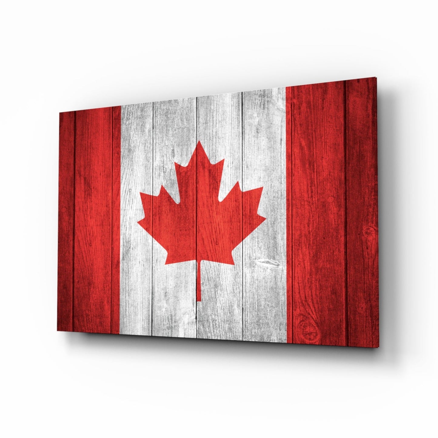 Canadian flag glass wall art displayed at an angle, showing red and white vertical stripes with a red maple leaf on a wooden texture background.