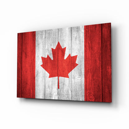 Canadian flag glass wall art displayed at an angle, showing red and white vertical stripes with a red maple leaf on a wooden texture background.