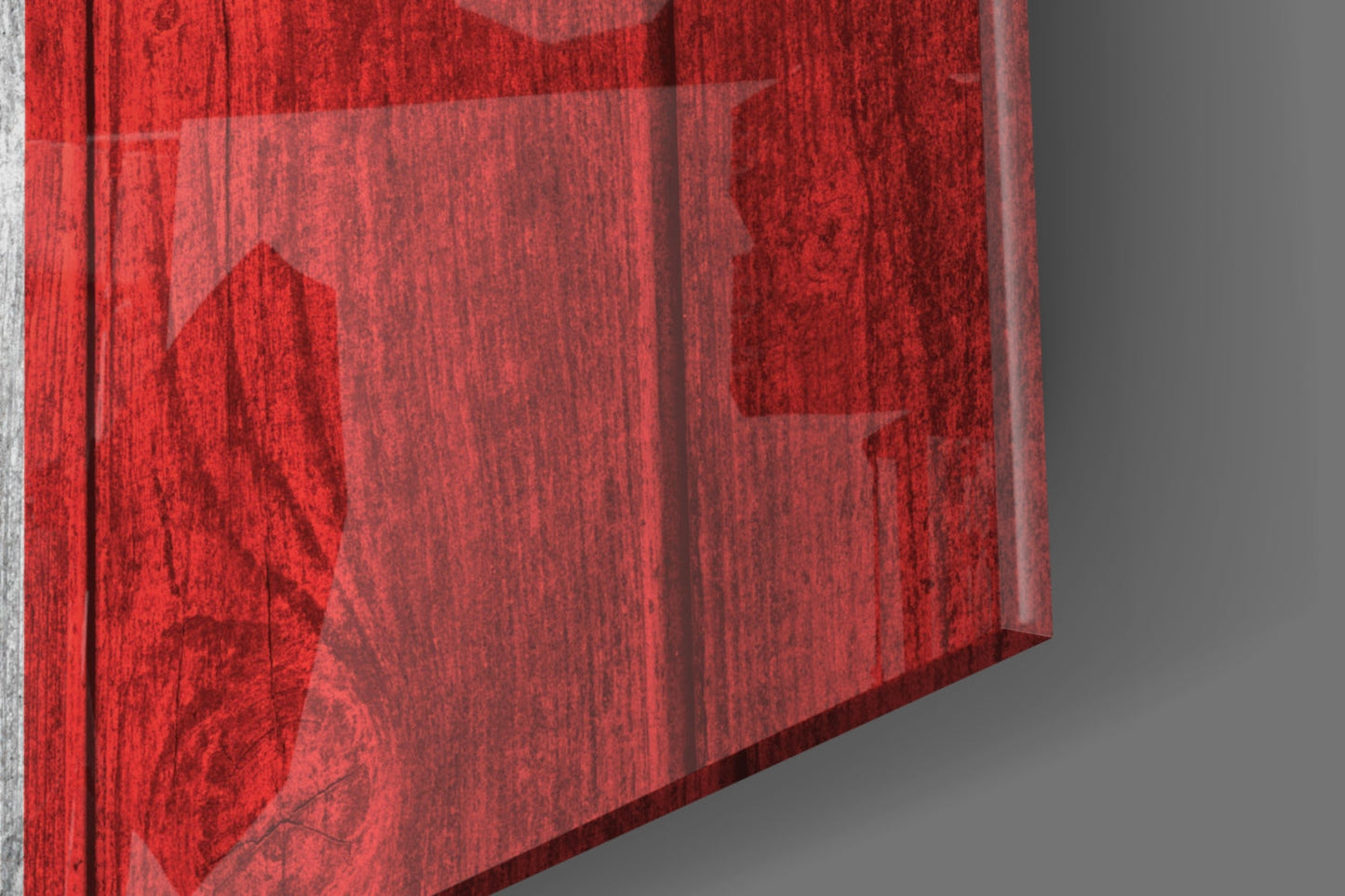 Close-up angled view of red textured glass sheet with maple leaf design against gray background.