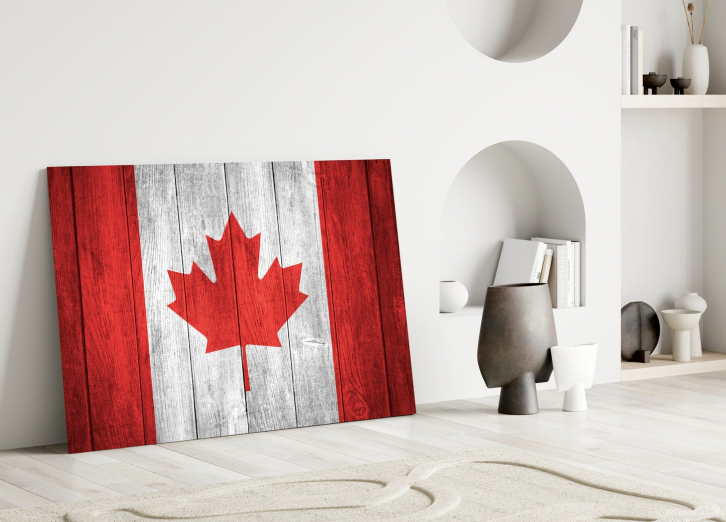 Canadian flag glass wall art leaning against white wall in minimalist interior with decorative objects and niches.
