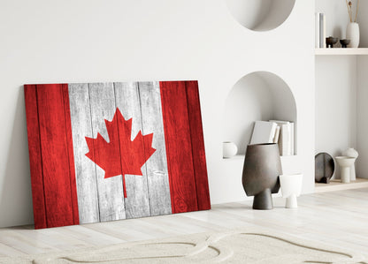 Canadian flag glass wall art leaning against white wall in minimalist interior with decorative objects and niches.
