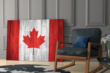 Canadian flag glass wall art displaying red and white maple leaf design installed in modern living room beside wooden chair.