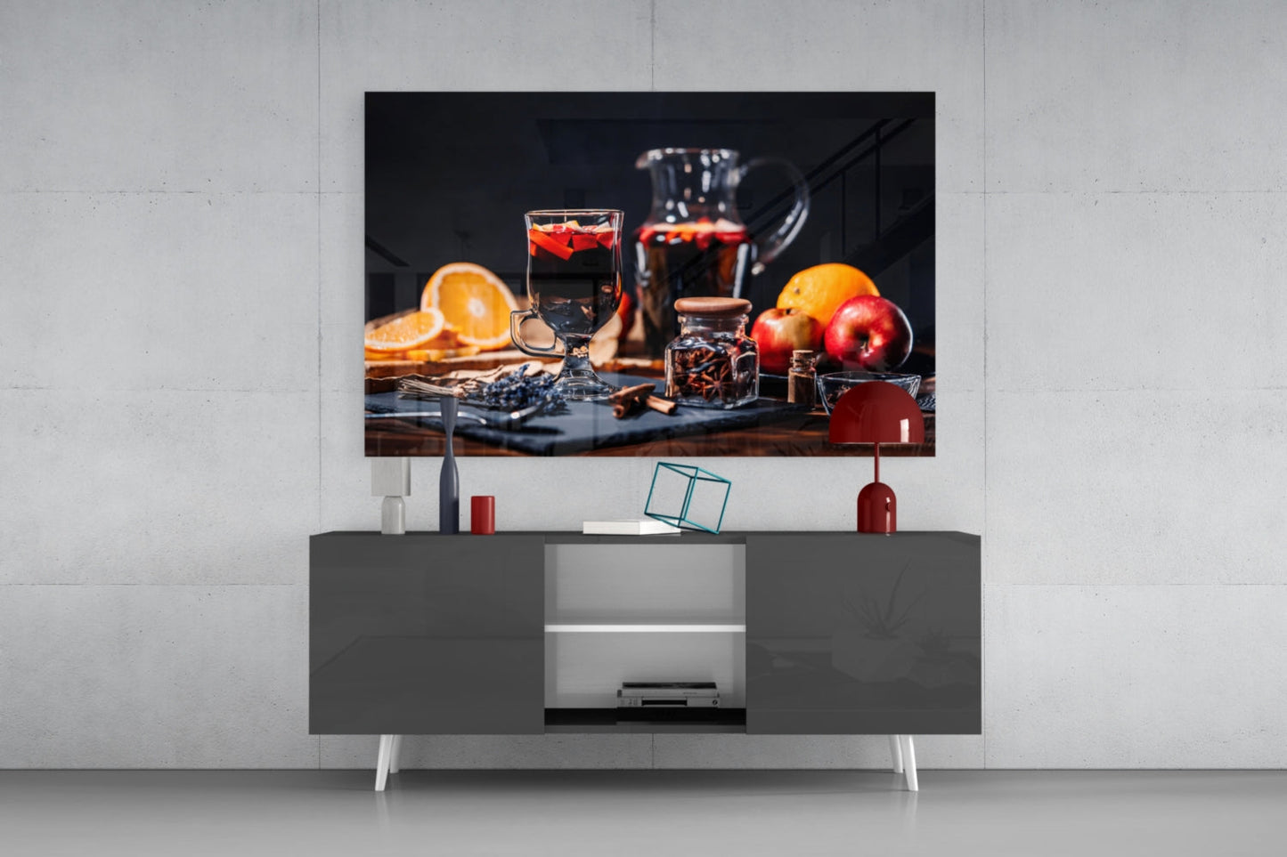 Noel Tea Glass Wall Art displayed above a gray media console, showing a still life of beverages, citrus fruits, and apples on dark background.