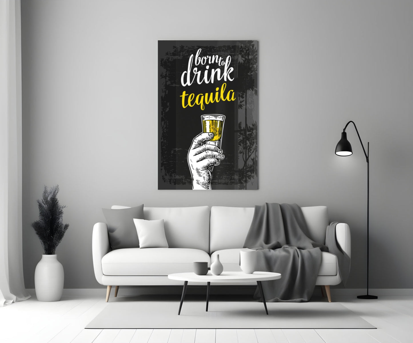Black canvas wall art with white and yellow text reading "born to drink tequila" and a sketched hand holding a filled glass, displayed above a white sofa in a modern living room.