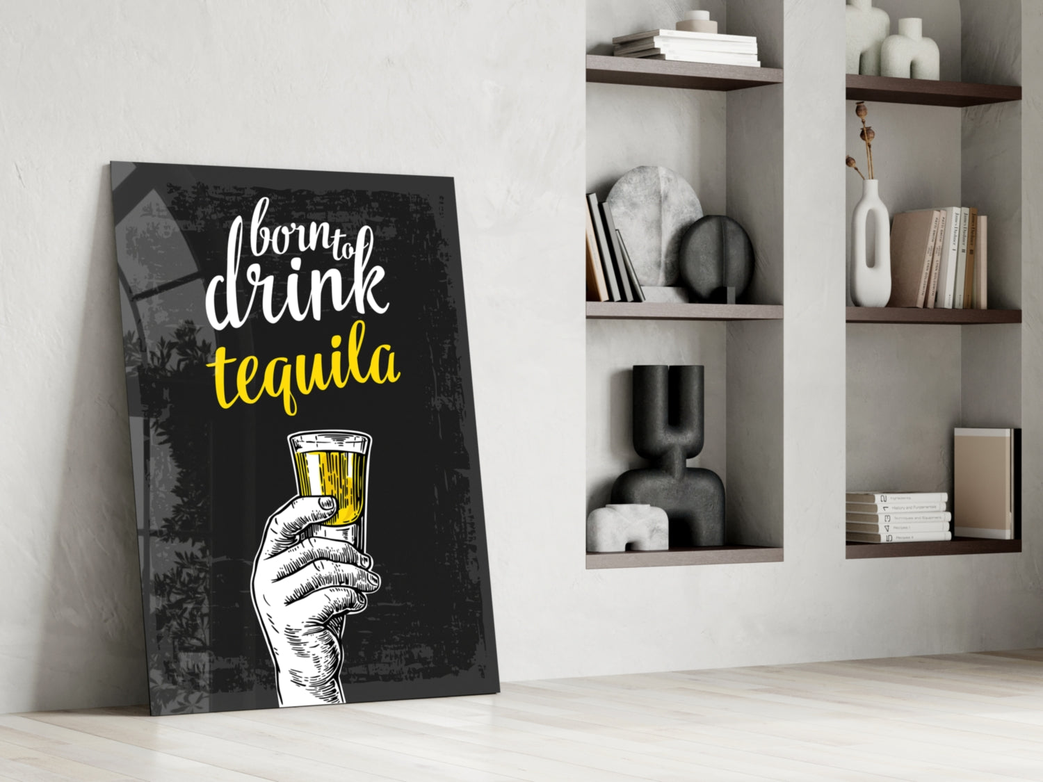 Black canvas tequila wall art with white and yellow text leaning against white wall beside styled shelving unit.