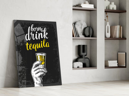 Black canvas tequila wall art with white and yellow text leaning against white wall beside styled shelving unit.