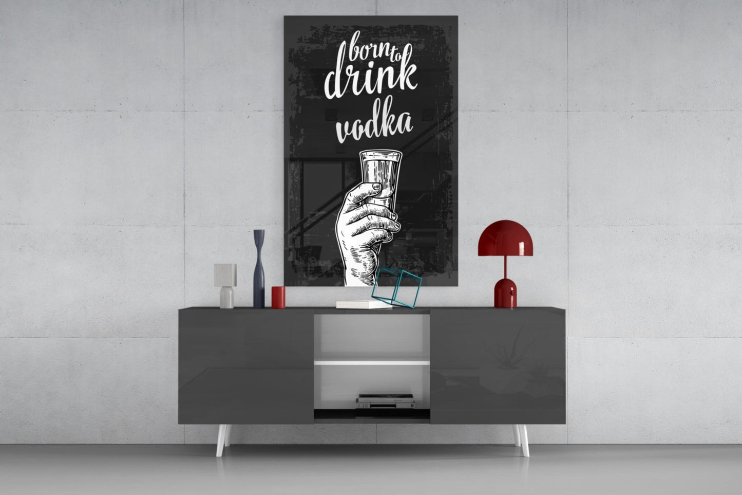 Black framed vodka wall art with white cursive text and hand illustration displayed above gray media console with red lamp and decorative objects.