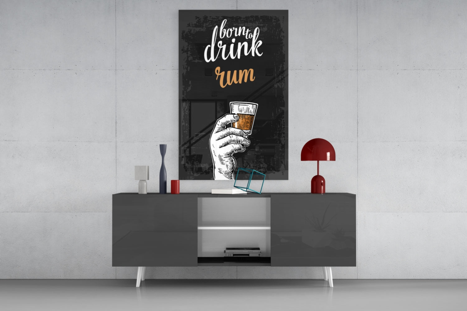 Black framed "I born to drink rum" wall art with hand holding glass displayed above gray media console with red lamp and decorative items.