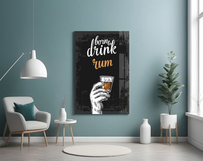 Black wooden rum wall art with white and gold hand-holding-glass illustration displayed in turquoise room with chair and plants.
