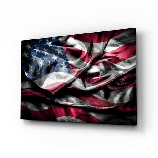 Angled view of glass wall art displaying a dramatically lit American flag in deep red, white, and blue tones with textured fabric appearance.