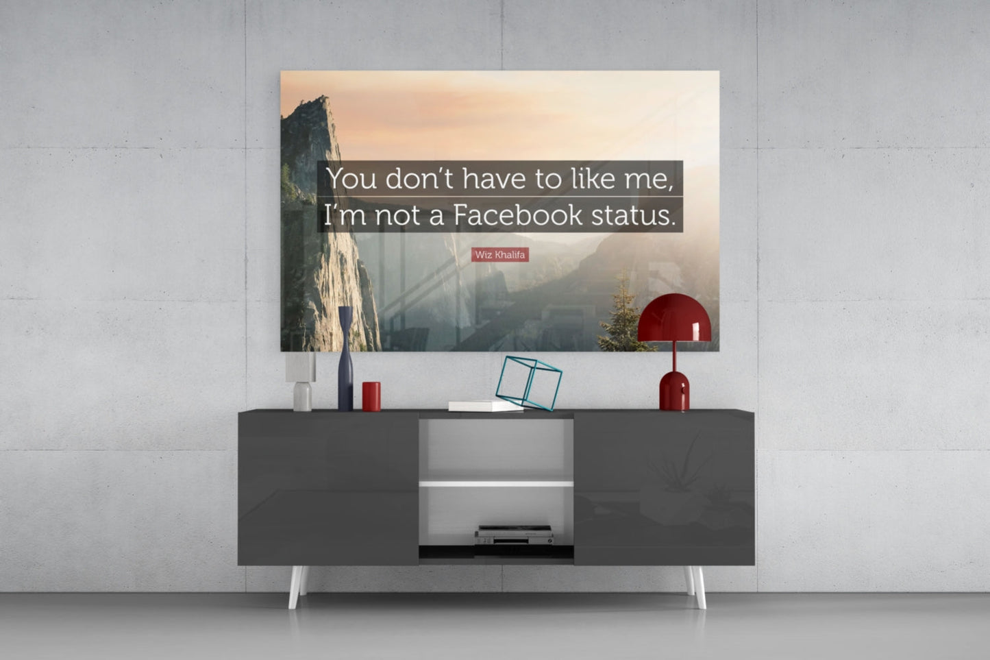Glass wall art with Wiz Khalifa quote displayed above dark console table with red lamp and decorative items.