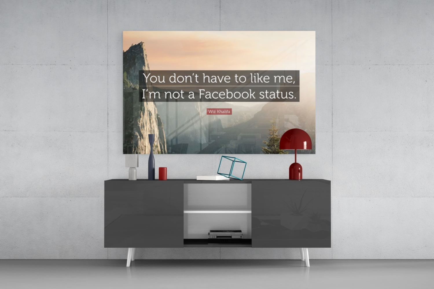Glass wall art with Wiz Khalifa quote displayed above dark console table with red lamp and decorative items.