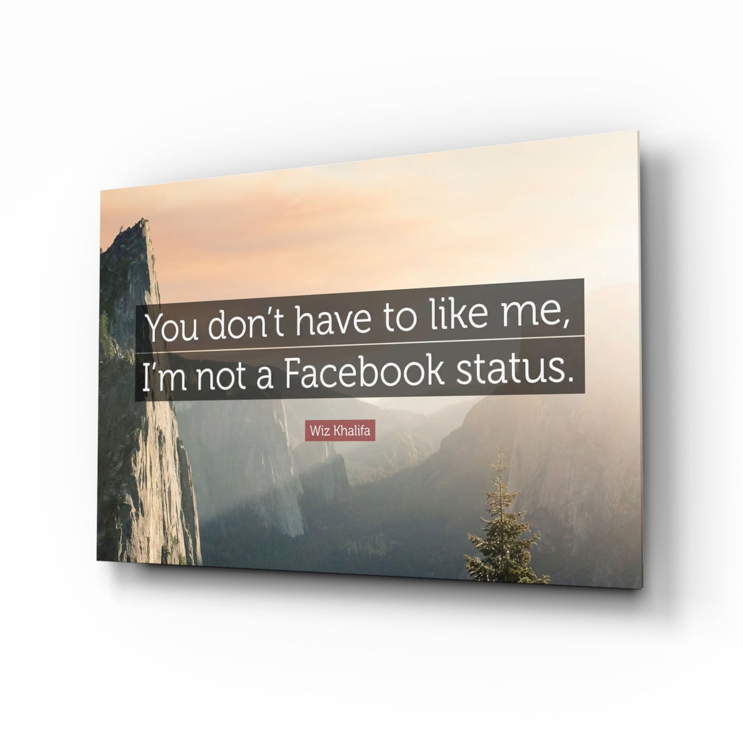 Glass wall art displaying a misty mountain valley landscape with white text quote and artist attribution, shown at an angled perspective.