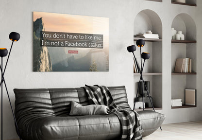 Glass wall art with Wiz Khalifa quote displayed above black leather sofa in modern living room with shelving.