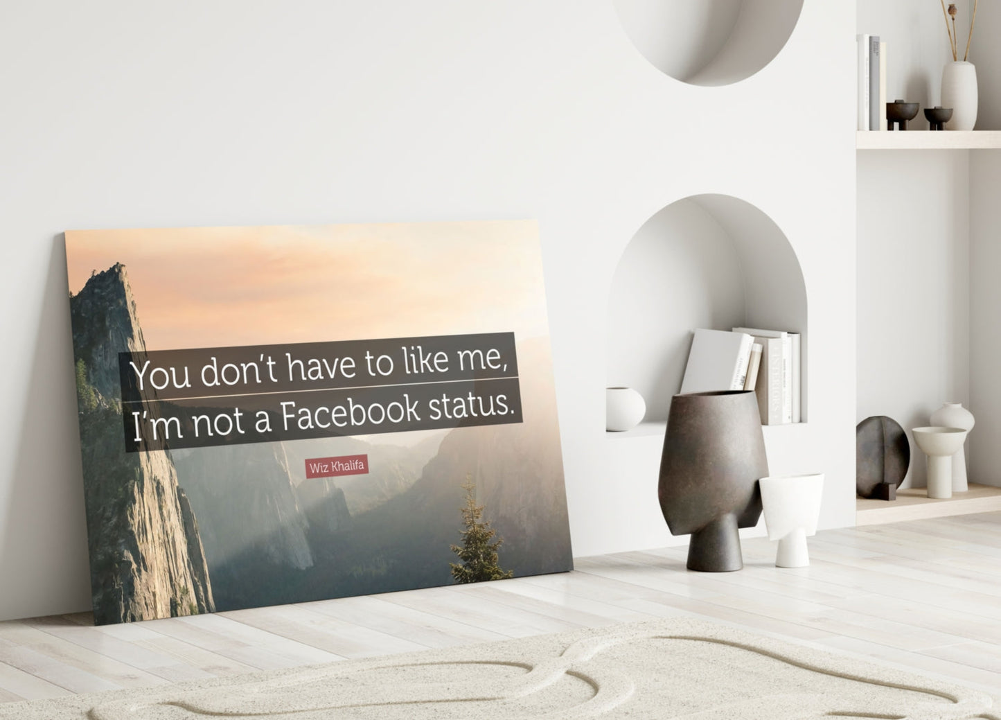 Glass wall art leaning against white wall displays mountain landscape with Wiz Khalifa quote in minimalist interior setting.