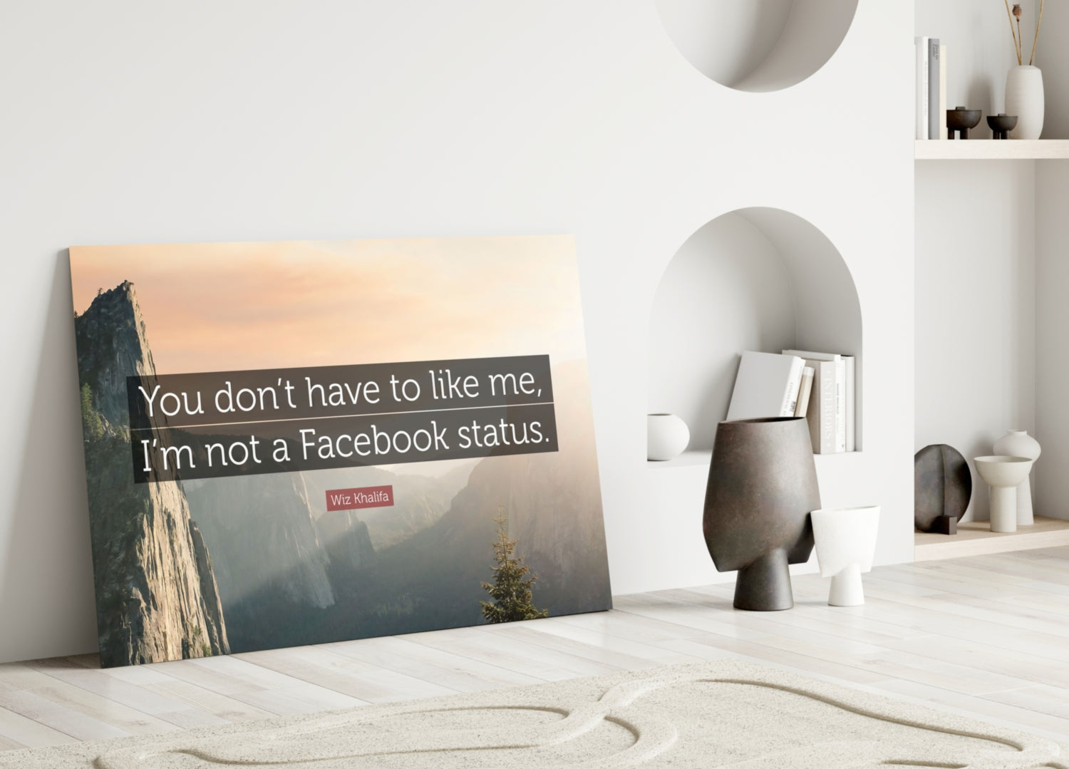 Glass wall art leaning against white wall displays mountain landscape with Wiz Khalifa quote in minimalist interior setting.