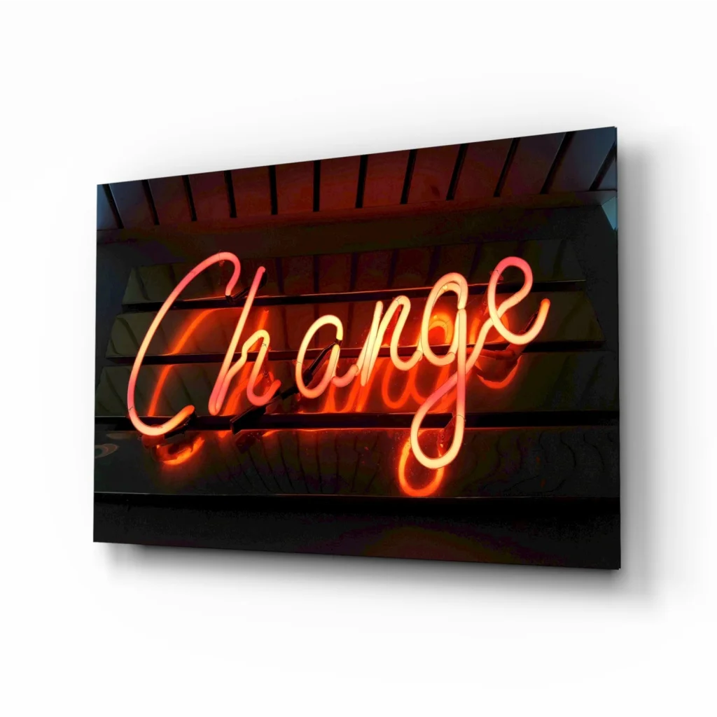 Glowing neon Change sign in orange pink cursive on dark background, glass wall art