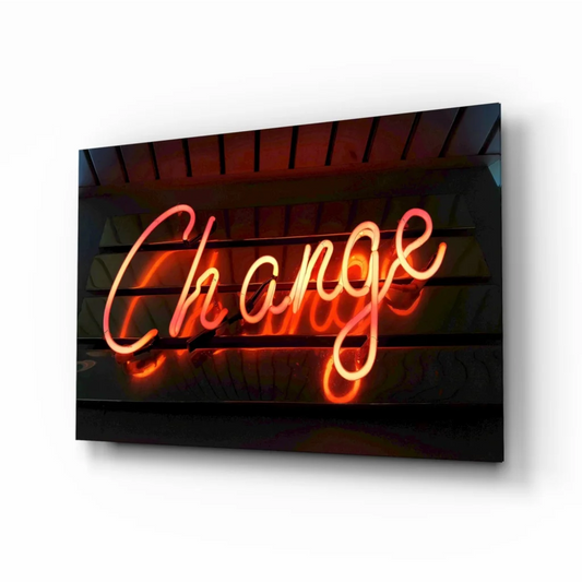 Glowing neon Change sign in orange pink cursive on dark background, glass wall art