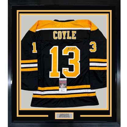 Framed black Boston Bruins hockey jersey number 13 with "COYLE" nameplate and signature, displayed flat against gray background with yellow and black border matting.