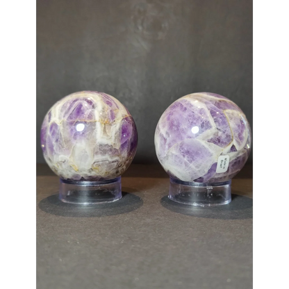 Two chevron amethyst polished sphere sculptures featuring purple and white crystalline patterns in polished form