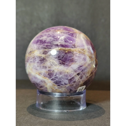Chevron amethyst polished sphere sculpture featuring intricate white and golden crystalline patterns on a clear stand
