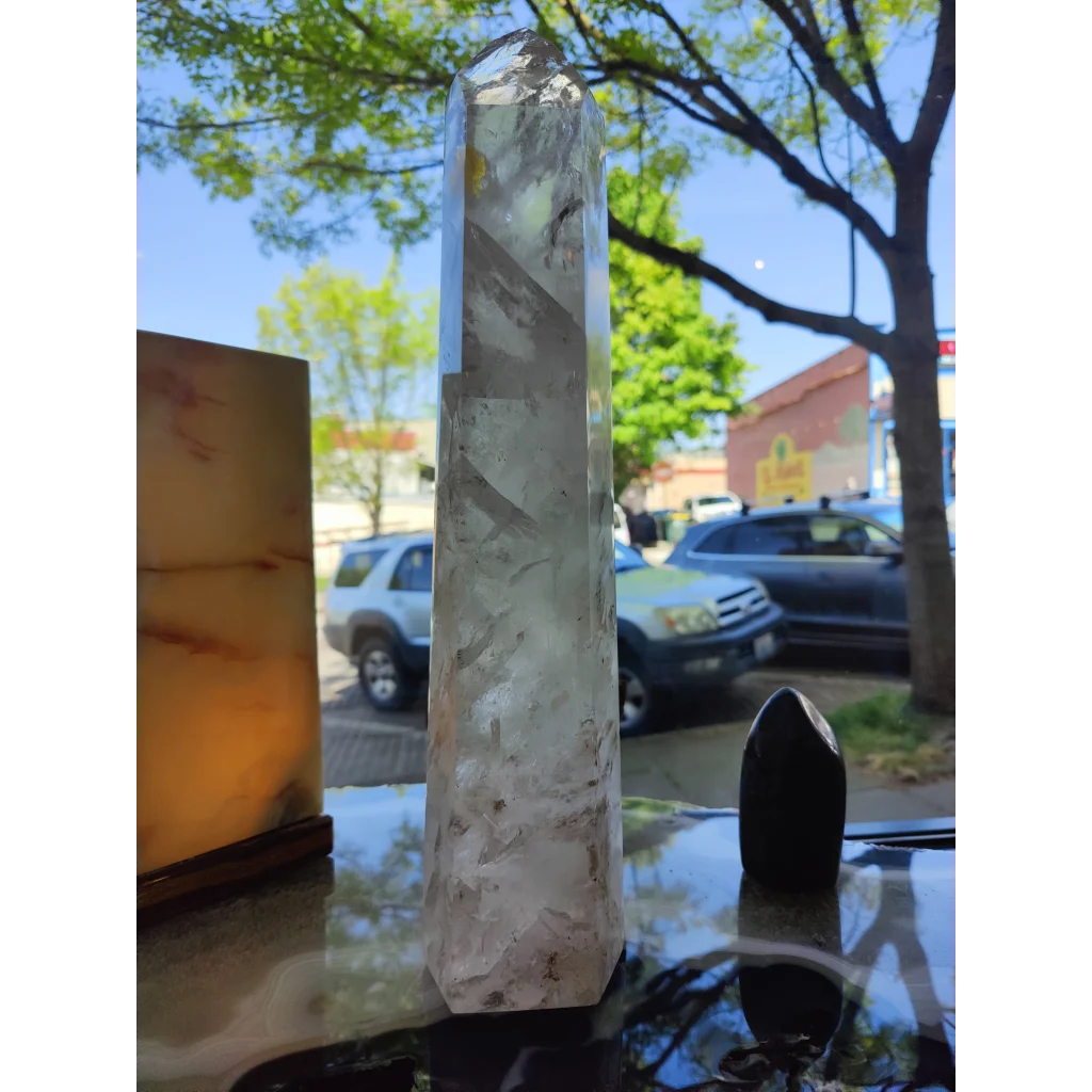 A clear quartz polished obelisk tower with natural inclusions and a faceted base weighing 5.35kg and 17.5 inches tall
