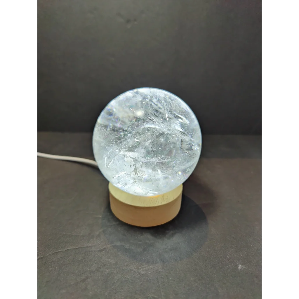 Clear quartz polished sphere sculpture featuring a clear crackled glass globe lamp with a wooden base