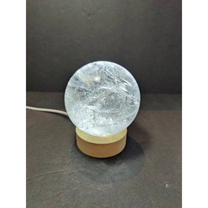 Clear quartz polished sphere sculpture featuring a clear crackled glass globe lamp with a wooden base