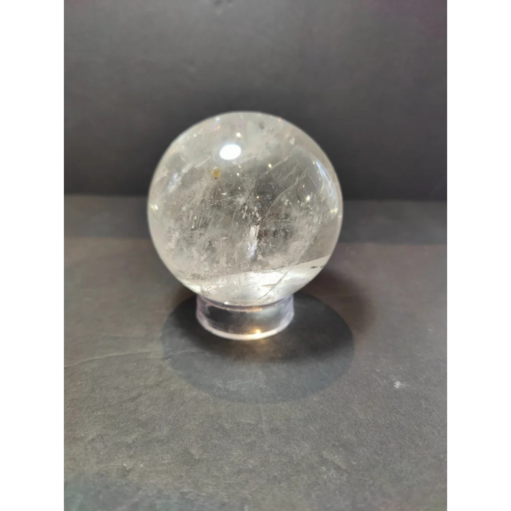 Clear quartz polished sphere sculpture with natural internal crystalline inclusions on a transparent acrylic stand