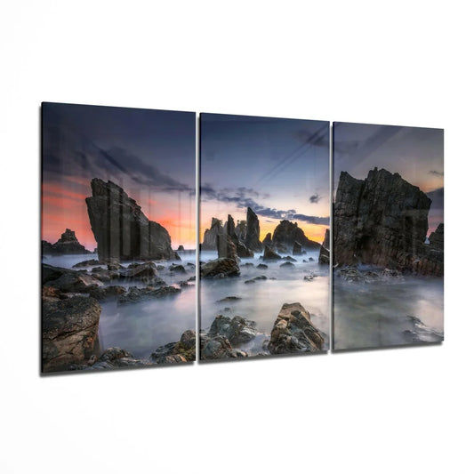 Three-panel coastal sunset wall art with rugged rocks and misty water