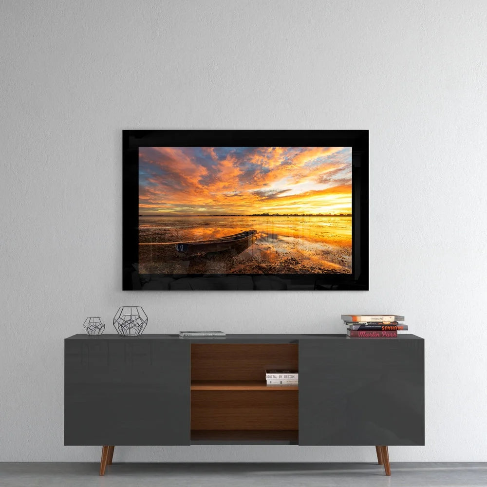 Vibrant orange yellow sunset over water with lone boat in black-framed glass wall art