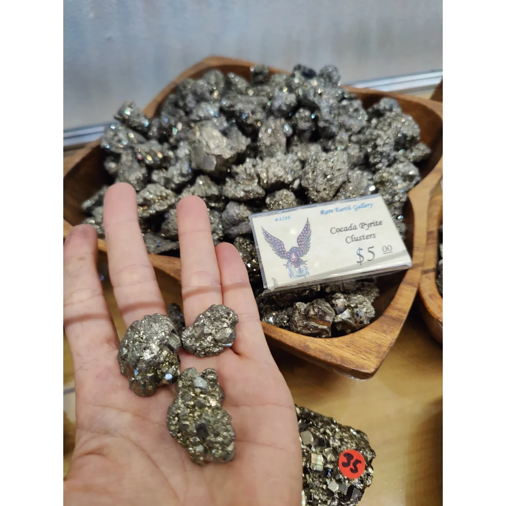 Hand holding cocada pyrite cluster with metallic silver-gray crystals