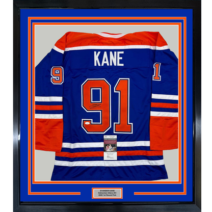 Framed Edmonton Oilers blue hockey jersey #91 with "KANE" nameplate and signature, displayed against blue and orange matting with JSA authentication certificate visible at center bottom.