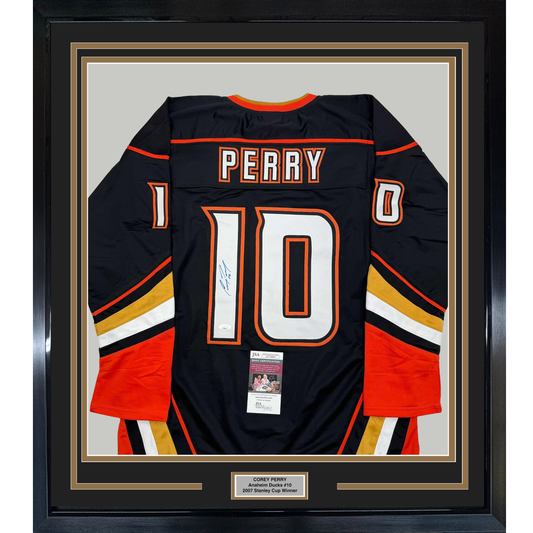 Framed black Anaheim Ducks hockey jersey number 10 with "PERRY" nameplate, signed, featuring red and gold striping with JSA authentication certificate visible.