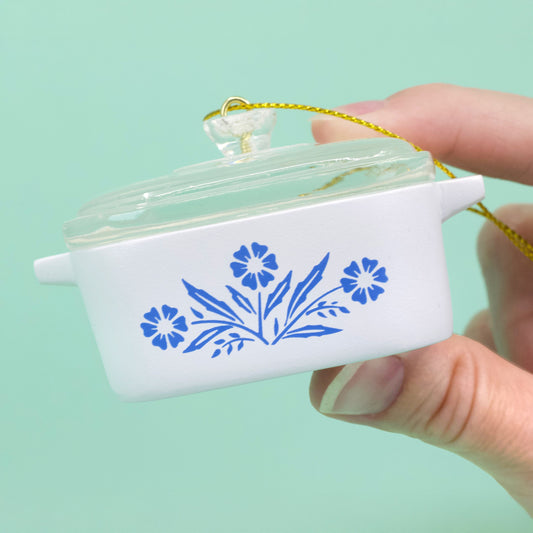 Cornflower casserole ornament held against a teal background